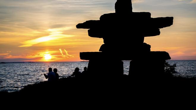 Silhouette of an inukshuk against a sunset