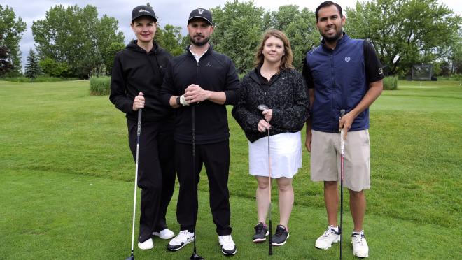 a group of four standing together on a golf green