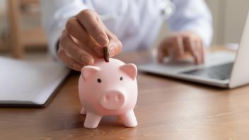 Person inserting a coin into a piggy bank.