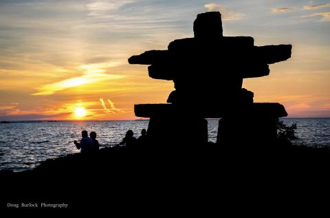 Silhouette of an inukshuk against a sunset
