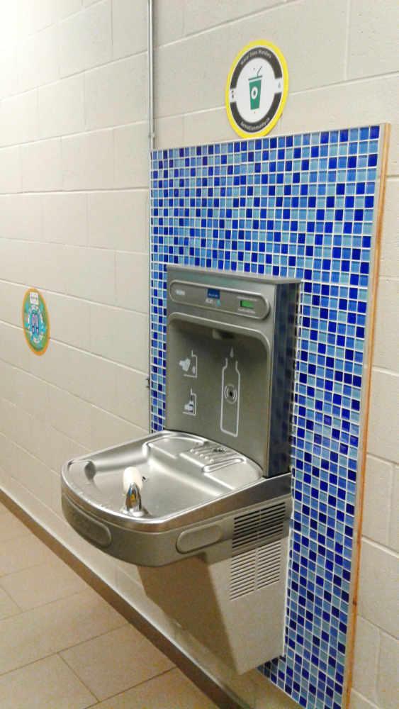 Metal water fountain on a wall with blue checkered tiles