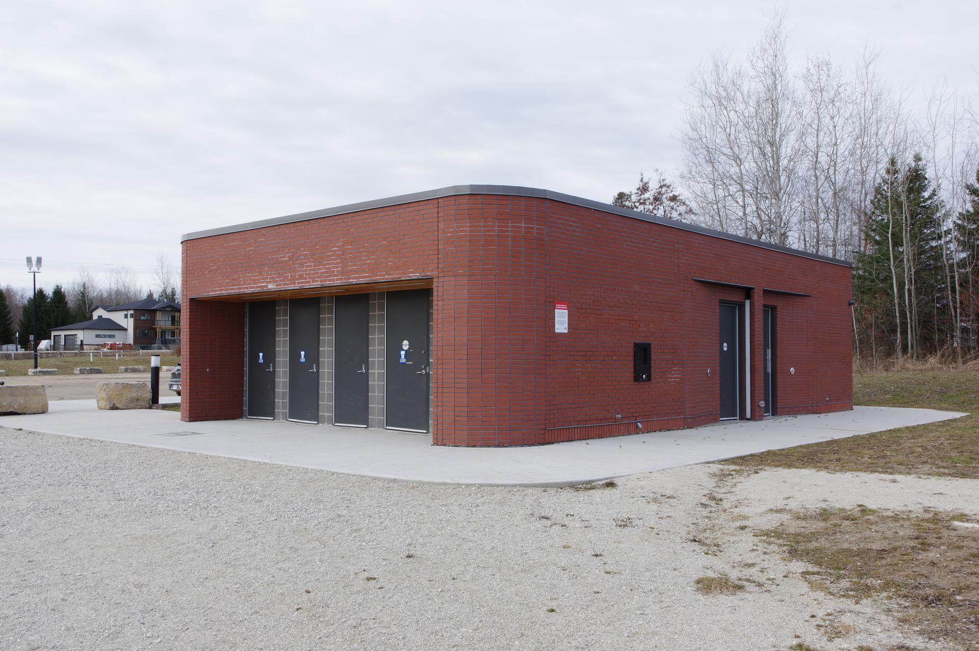 A rectangular brick building with four black doors on the front and one on the side